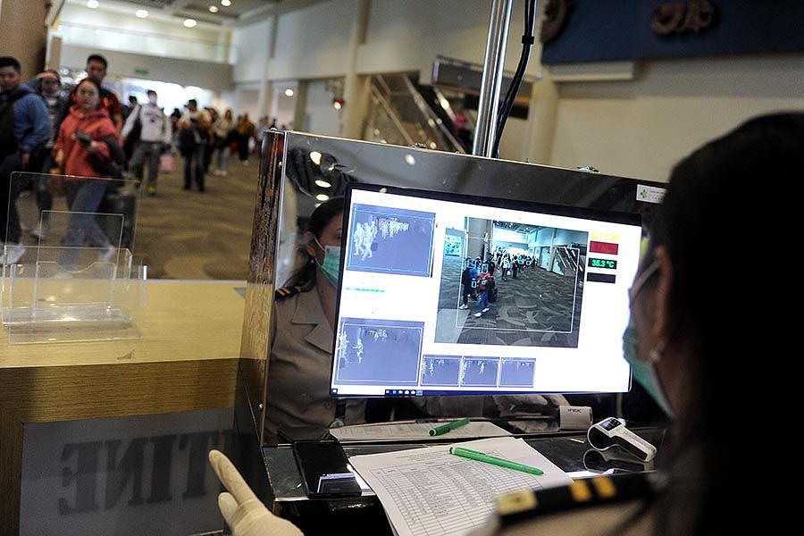 Officers monitor the body temperature of passengers using a body temperature scanner at the International Arrival Terminal I Gusti Ngurah Rai International Airport, Bali