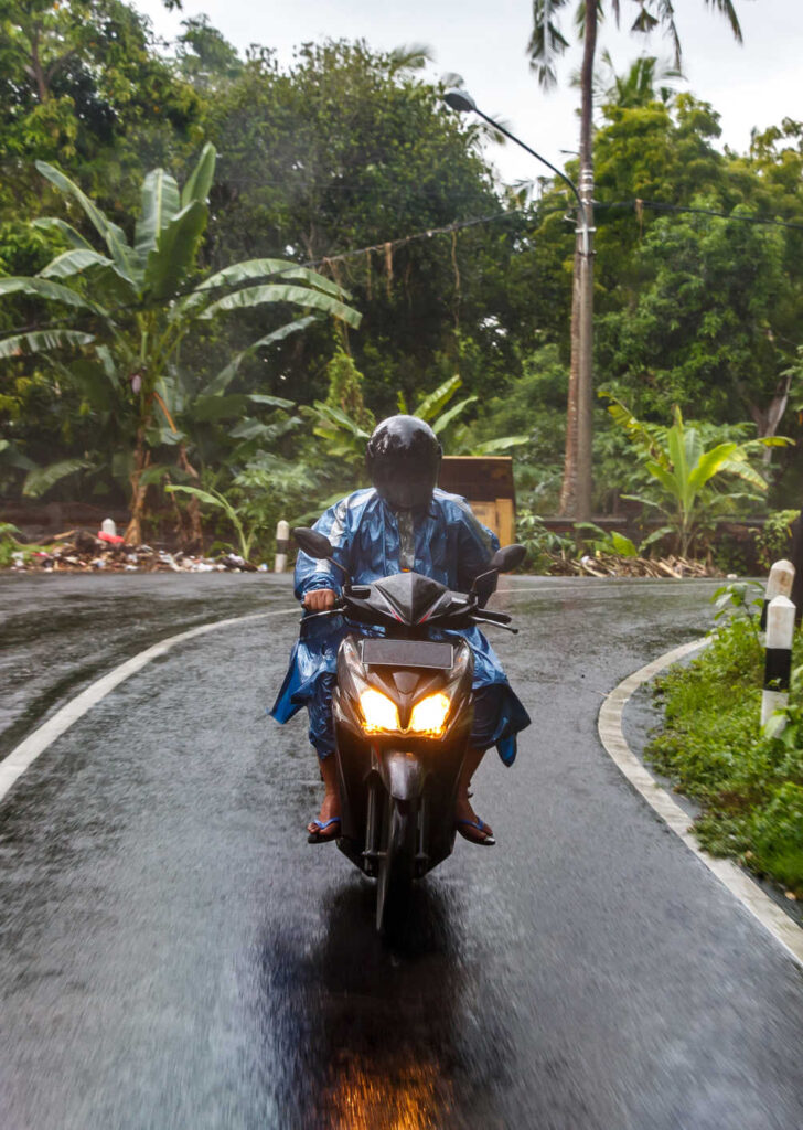 bali local wearing rain jacket on scooter in rain