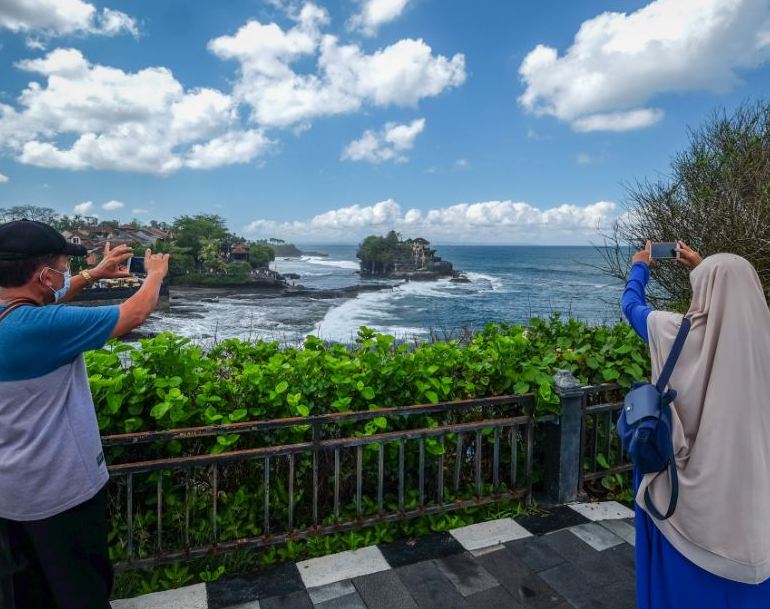 locals taking photos on phones by beach in Bali