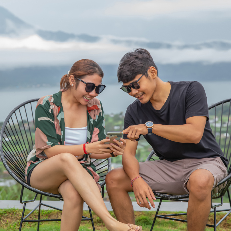 Indonesian Couple Watching Viral Video on Smartphone During Staycation.