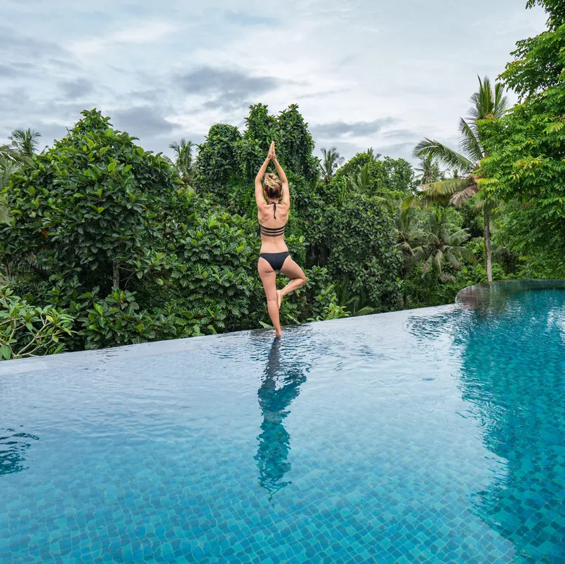Young woman standing on the edge of an infinity pool, Ubud, Bali