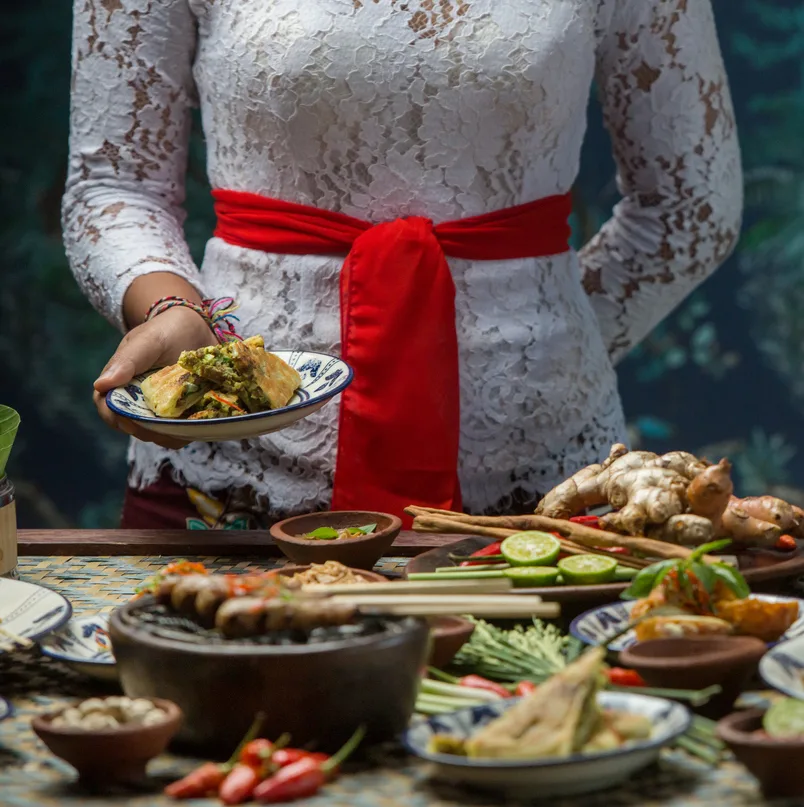 Indonesian cuisine - Many traditional Balinese dishes on the table. Waitress is serving food