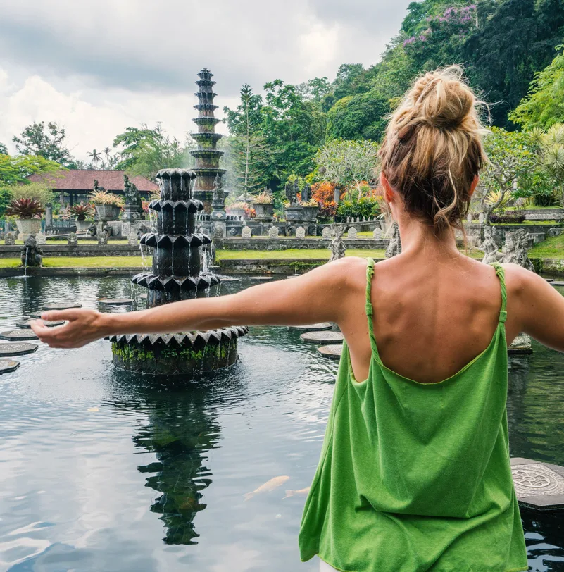 Young woman embracing Tirta Gangga temple, Bali, Indonesia