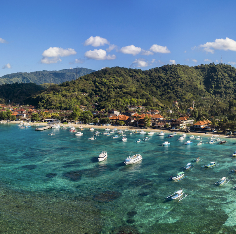 Aerial drone panorama taken by drone of the peaceful village of Padangbai located on the Eastern shore of Bali with the harbour being the main departure access to Lombok in Indonesia