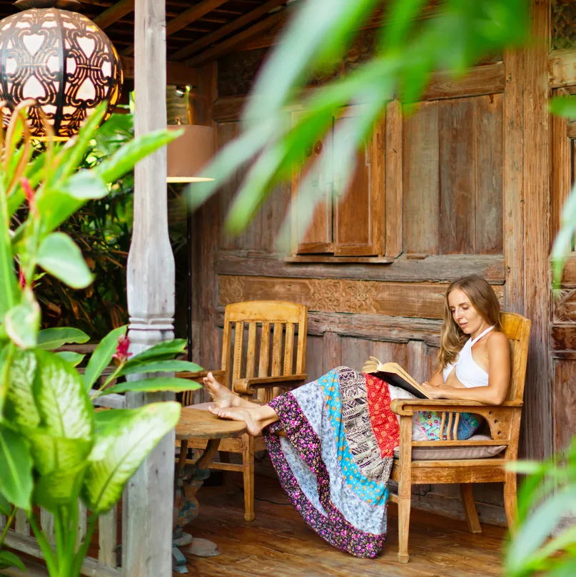 Young woman read paper book on outside veranda