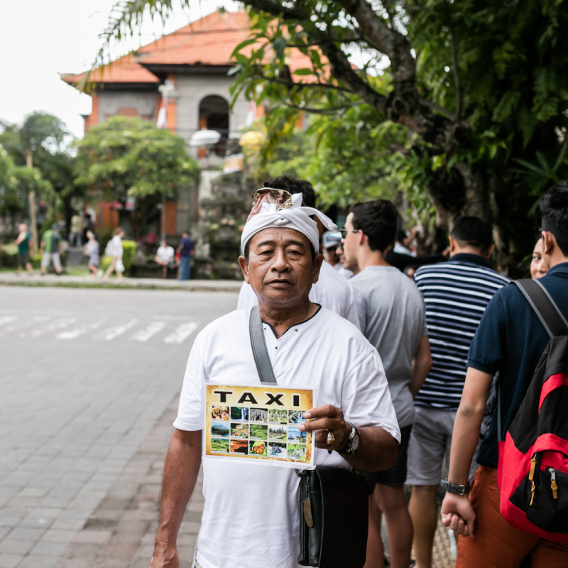 Bali-Taxi-Driver-Holds-Taxi-Sign-In-Ubud