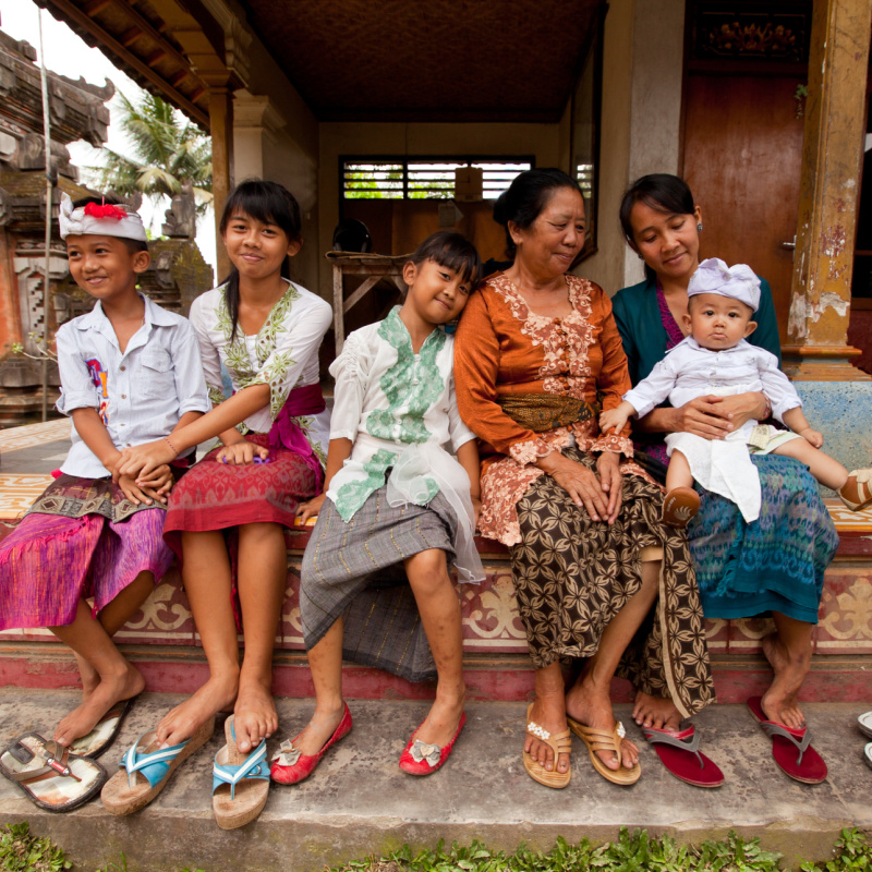 Balinese-Family-In-Traditiona-Clothes-Sit-Outside-Their-House