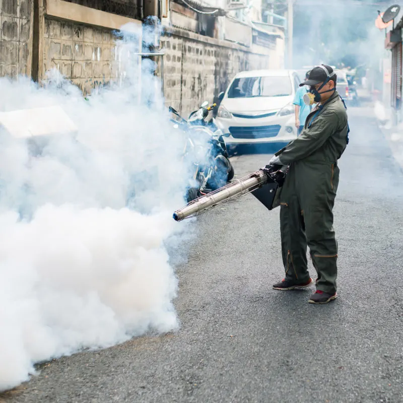 Health-Worker-Fogs-Mosquitos-Away-On-Street-