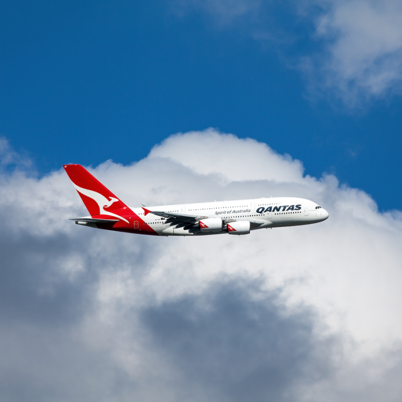 Qantas-Airplane-Flies-Through-White-Clouds-In-Blue-Sky
