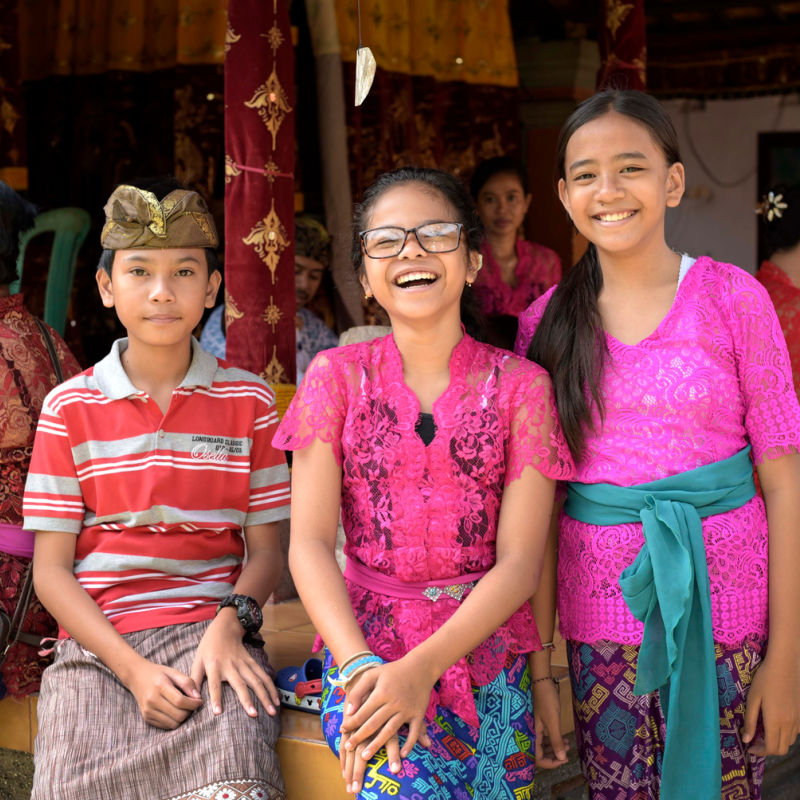 Three-Young-Balinese-People-Smile-At-The-Camera-Wearing-Traditional-Clothing