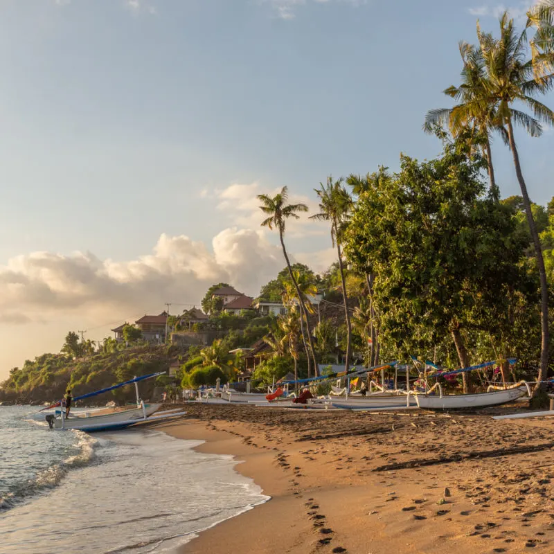 Amed-Beach-At-Sunset-With-Palm-Trees-and-Traditional-Boats