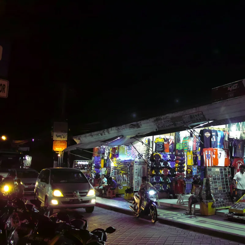 Cars-And-Moped-Drive-On-Bali-Street-By-Night-Market
