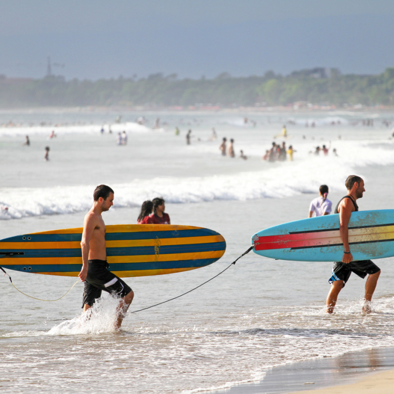 Two-Surfers-Carrying-Surfboards-Exit-The-Waves-Onto-Kuta-Beach-Bali