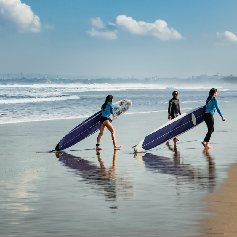 Two-Surfers-In-Bali-Leave-The-Sea-With-Their-Surfboards-After-Lesson