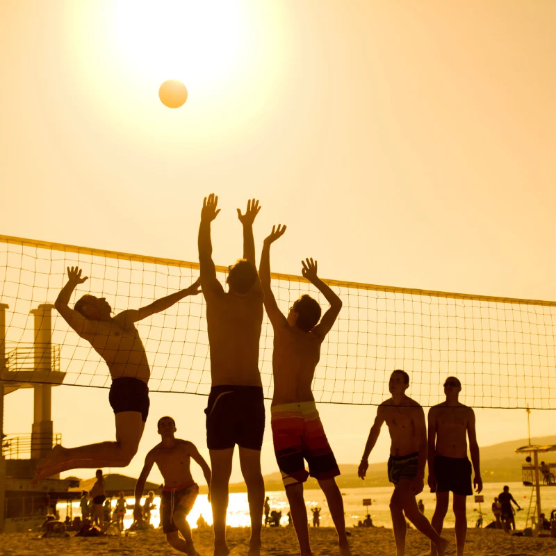 People-Play-Beach-Volleyball-At-Sunset