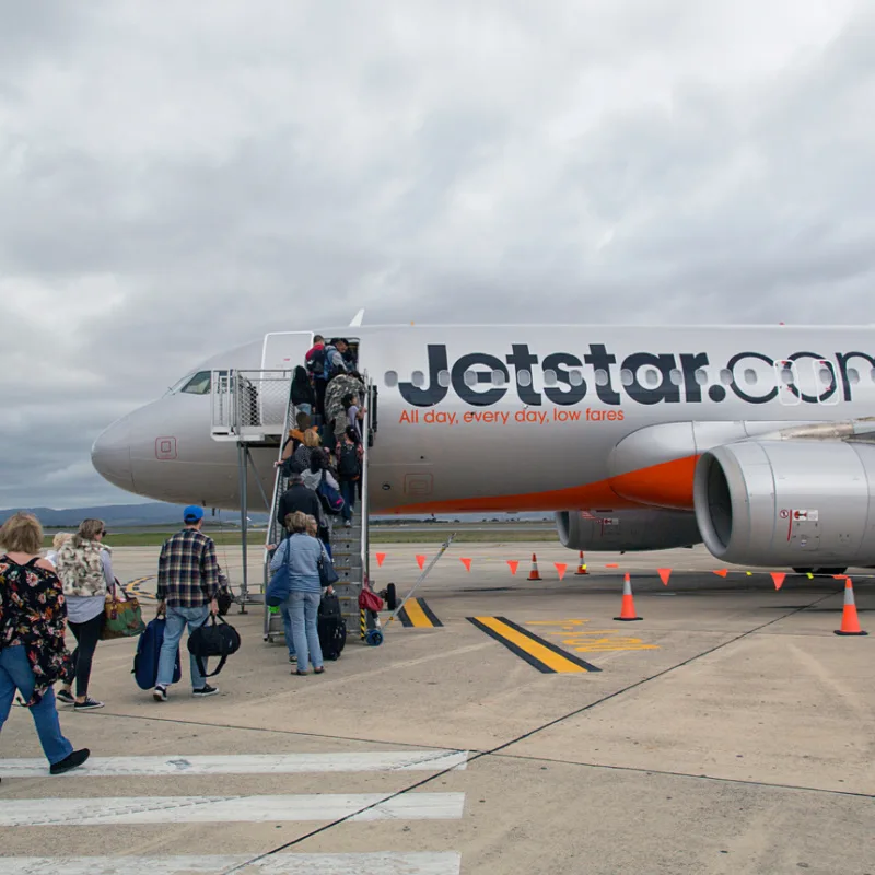 Travelers-Board-A-JetStar-Airplane-On-Airport-Runway