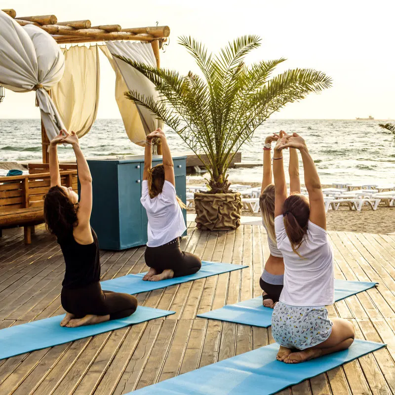 People-Do-Yoga-In-Back-At-Beach-Club-Wellness