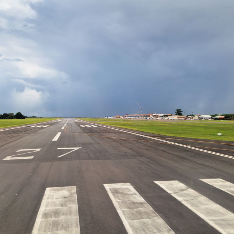 Runway-At-Bali-Airport-With-Terminal-Building-In-The-Distance-Under-Grey-Skies