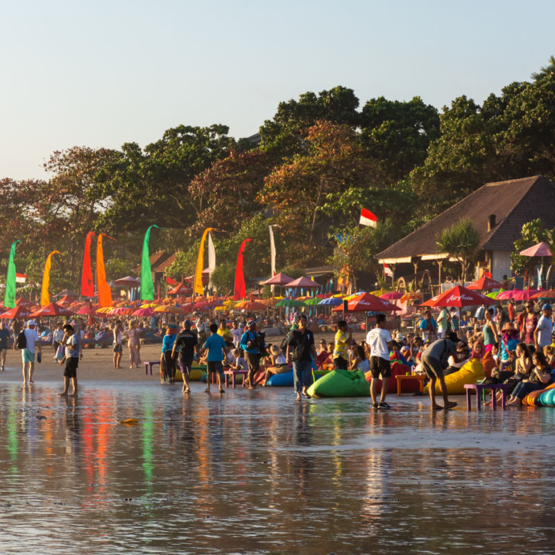 Tourists visiting the bustling Seminyak beach in Bali