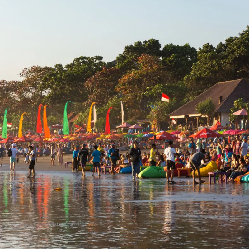 Tourists visiting the bustling Seminyak beach in Bali