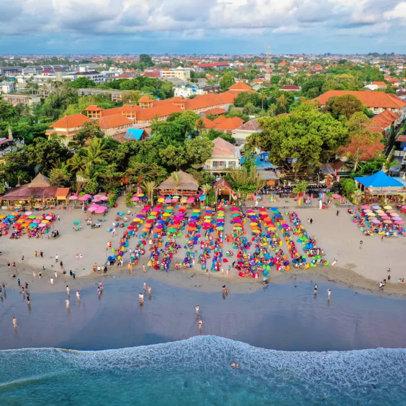 Ariel shot of Seminyak Beach in Bali tourists sit on colourful bean bags watching ocean