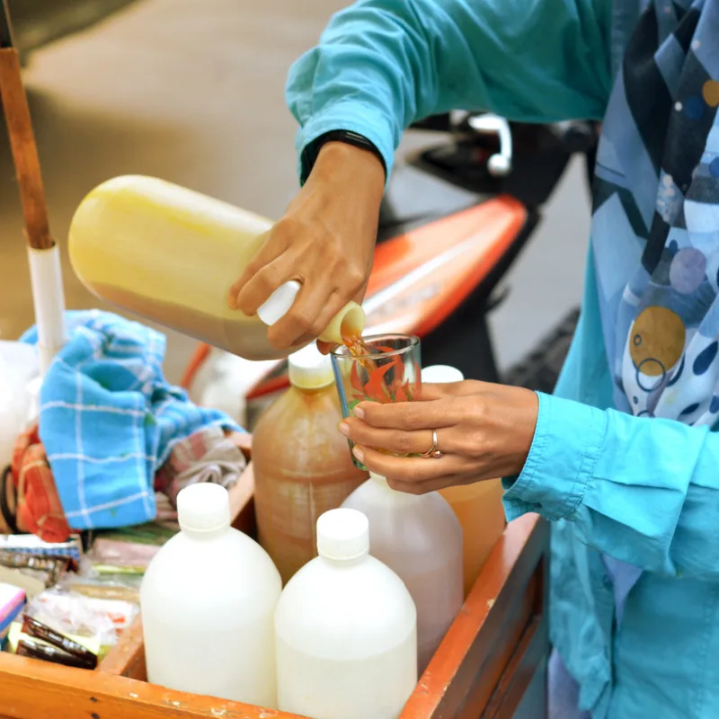 Bali Medicine Woman Pours Treatment For Illness Into Glass.