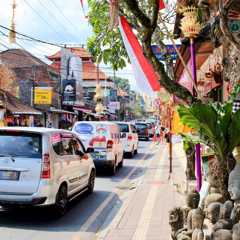 Busy Street In Ubud Bali With Traffic Cars And Vans On Tourist Shopping Road.