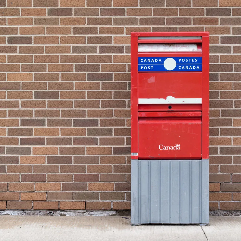 Canada Post Postbox against brick wall.