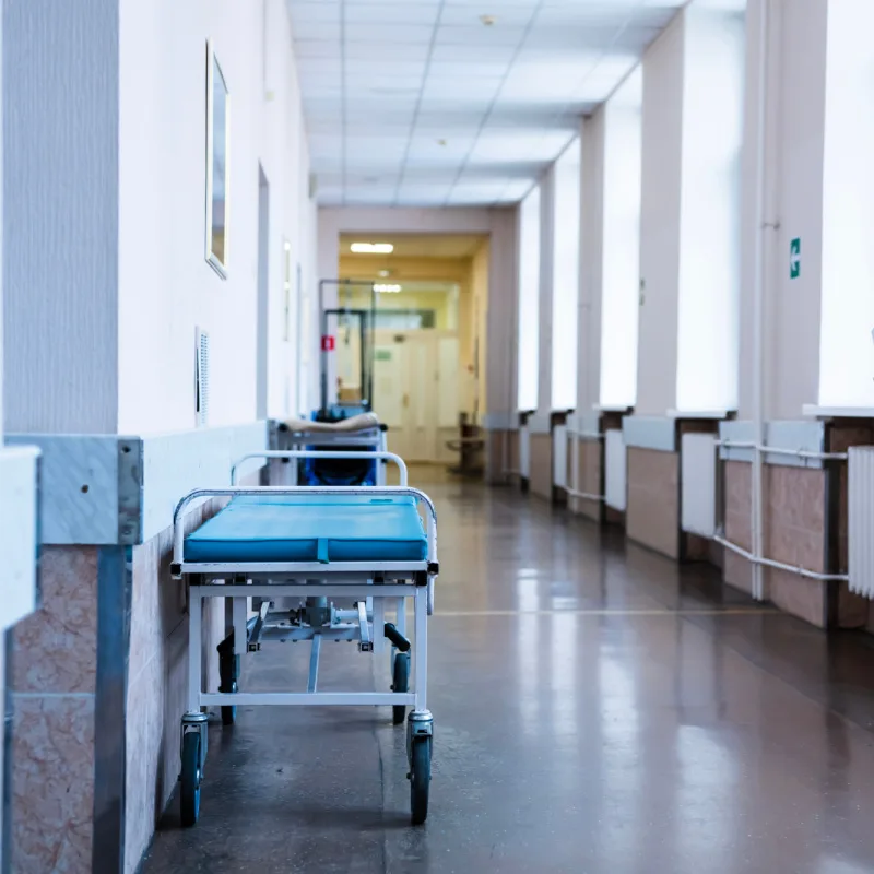 Long View Of Empty Hospital Corridor With Bed Against The Wall