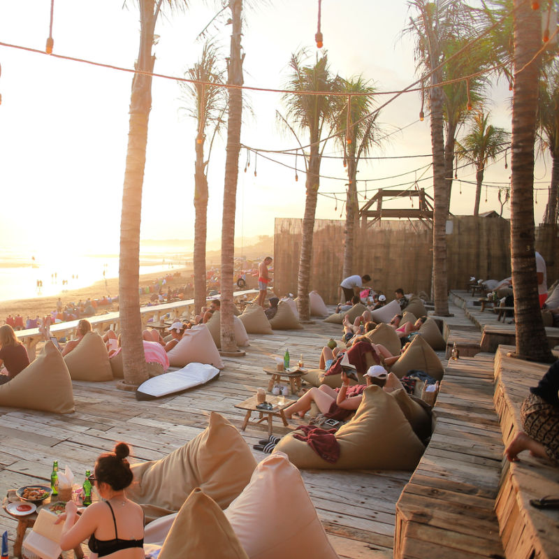 Travelers And Tourists Sit On Bean Bags At Sunset At Bali La Bris Beach Club