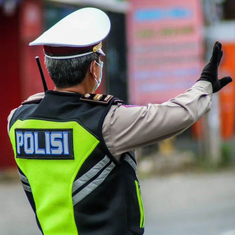 Bali Traffic Police Officer Stands Away From Camera Looking At Traffic.