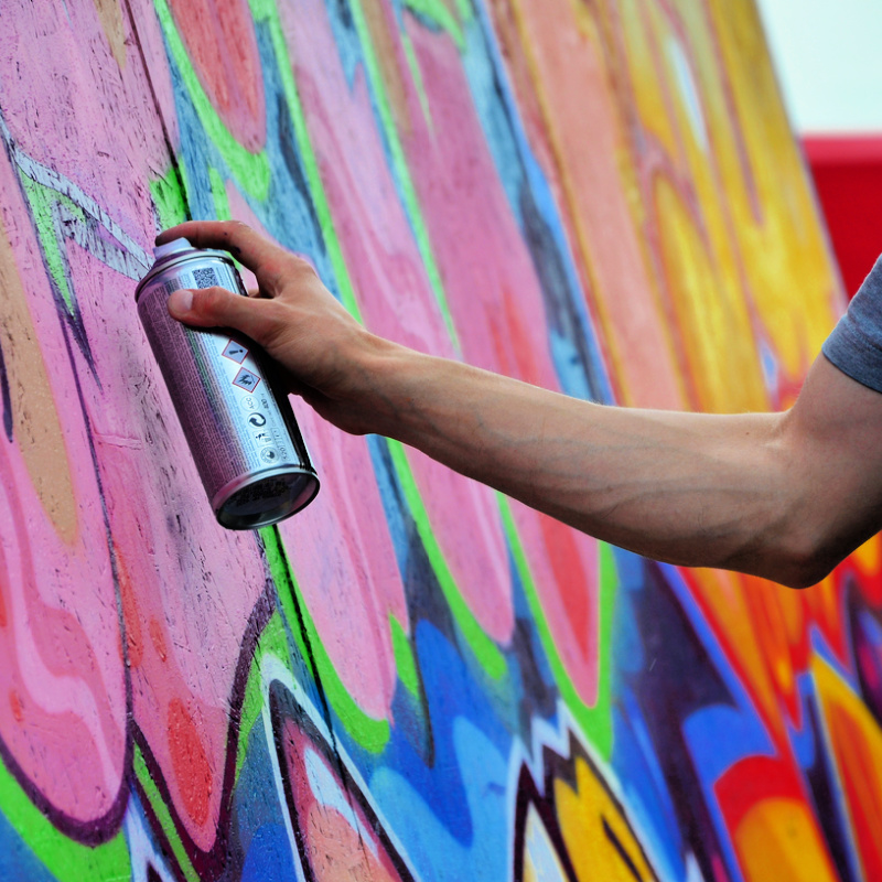 Close-Up-Of-Arm-And-Hand-Spraying-Graffiti-On-Wall