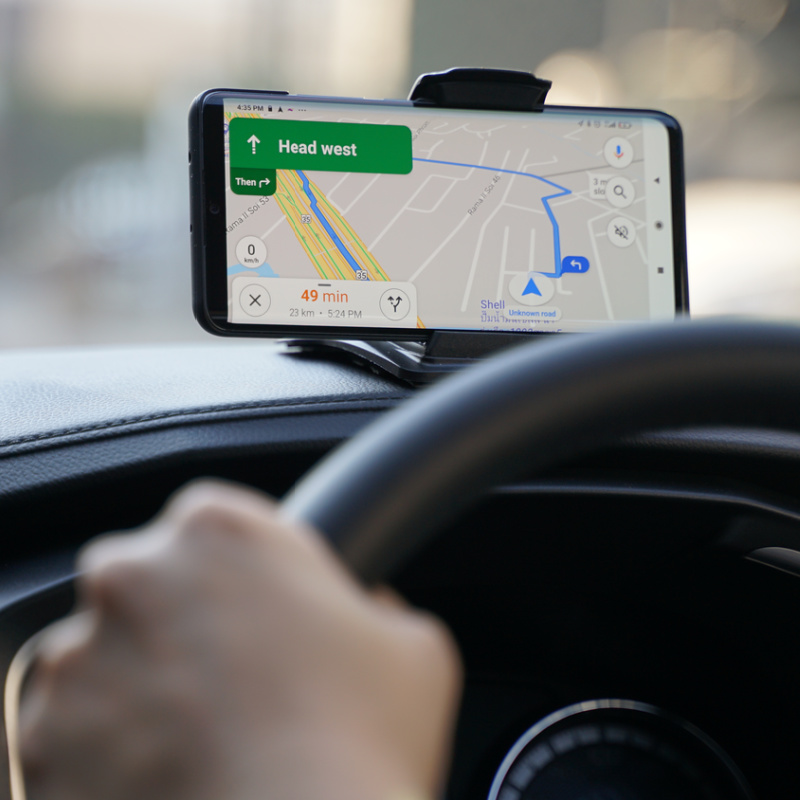 Close Up Of GoogleMaps on Phone In Car Dashboard While Driver Looks Ahead