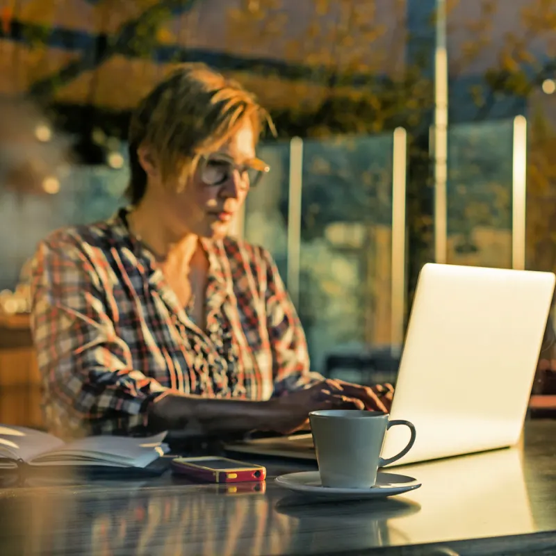 Digital Nomad Woman Works on her laptop at a cafe with a coffee