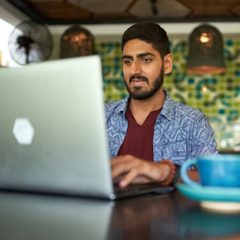 Un nómada digital trabaja en su portátil en una cafetería de Bali con una taza de café