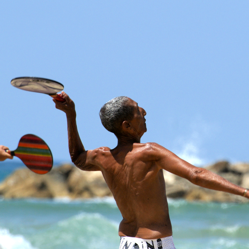 Elderly Man Plays Tennis On A Beach Close To The Sea