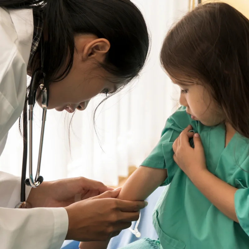 Female Doctor In Bali Hospital Looks At Young Girl's Arm