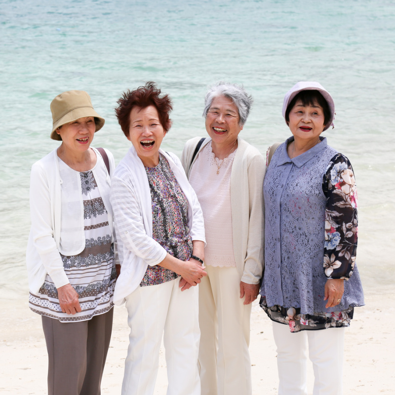 Four Japanese Women Stand On Beach Looking Happy