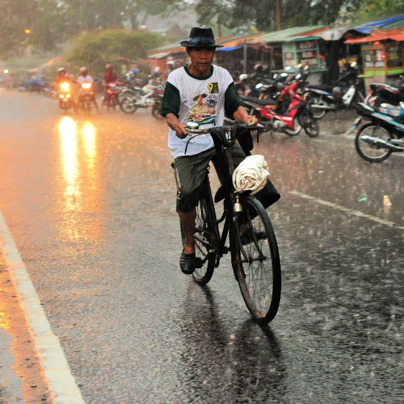 Indonesian-Man-Rides-A-Bicycle-Through-A-Street-In-The-Heavy-Storm-Rain