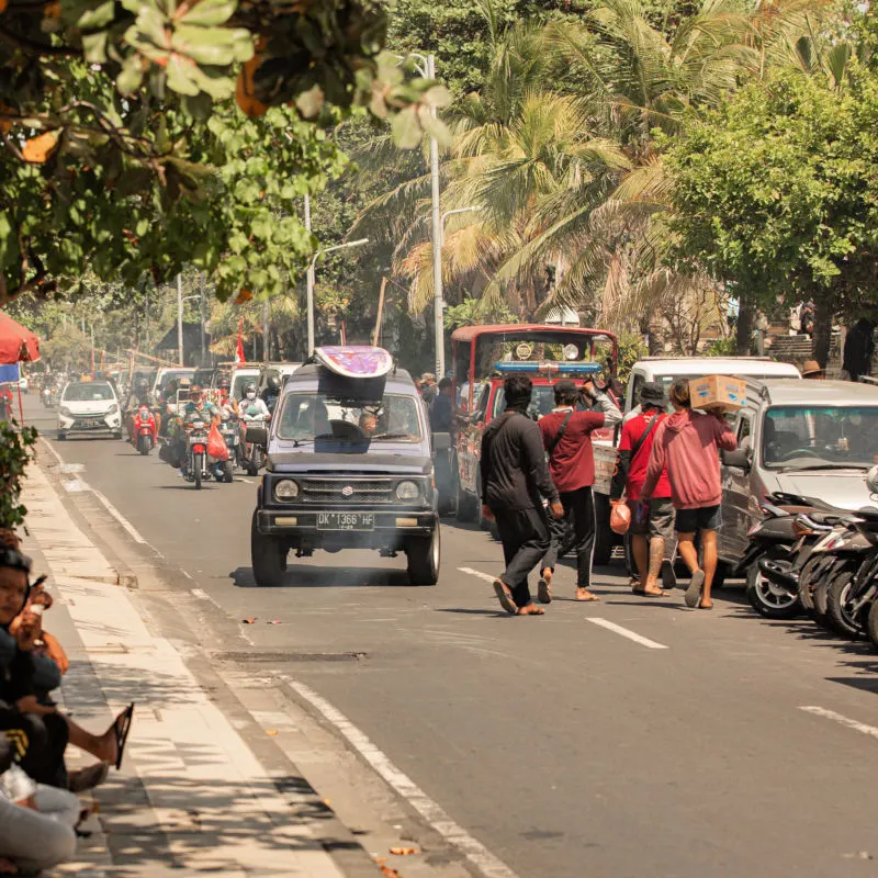 Local Men Walk Down Street Busy With Traffic Near Kuta in Bali