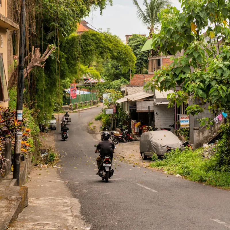 Moped Drives Down Quiet Village Road Street In Bali.jpg