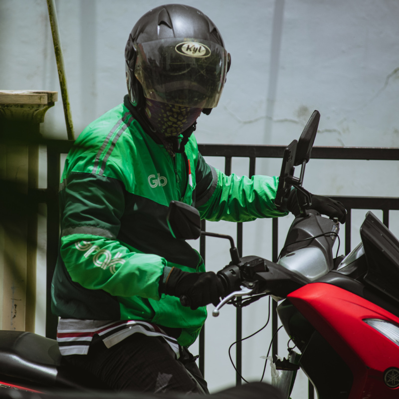 Moped-Taxi-Driver-Wears-Helmet-And-Green-Jacket-In-Bali