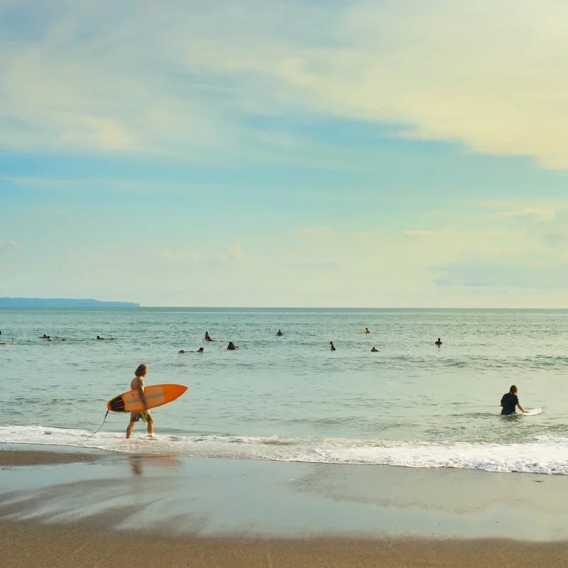 Surfers Head Out To Catch Some Waves In Bali At Sunset