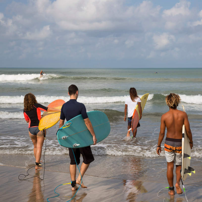 Tourists in Bali Walk Away From Beach into The Sea For a Surf Lesson