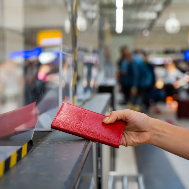 Traveler-Hands-Over-Red-Passport-At-Airport-Immigration-Counter