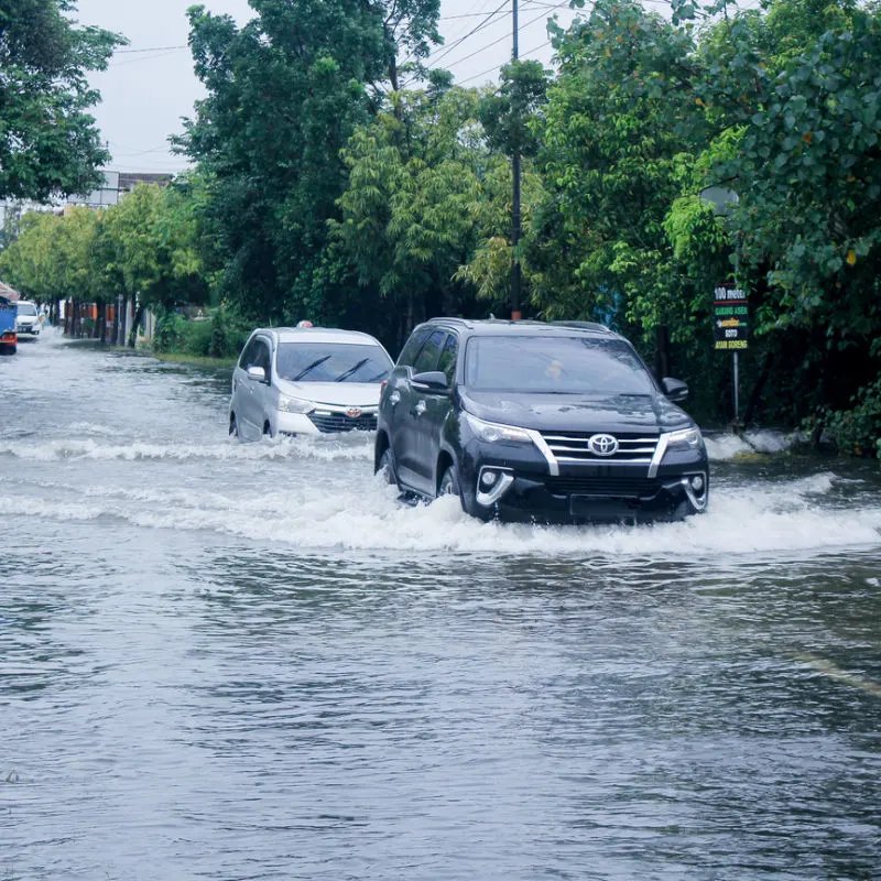 Cars Drive Through Flood Water In Bali.