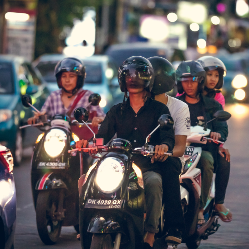 Moped Drivers Sit In Bali Traffic In Early Evening Nighttime