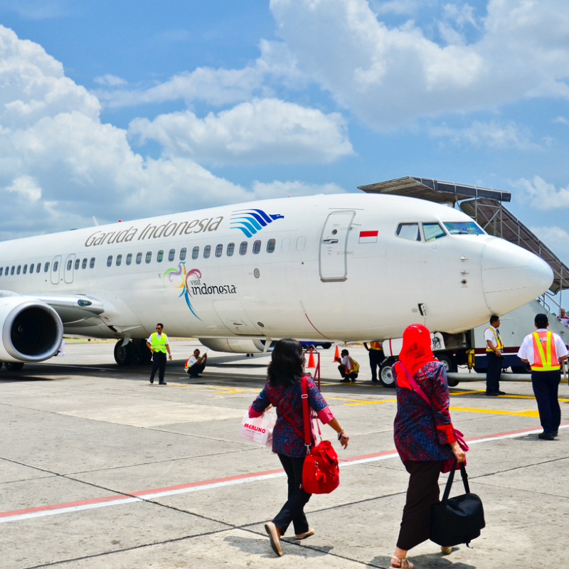 Passengers Walk Across Aiport tarmac Towards Garuda Indonesia Airplane.