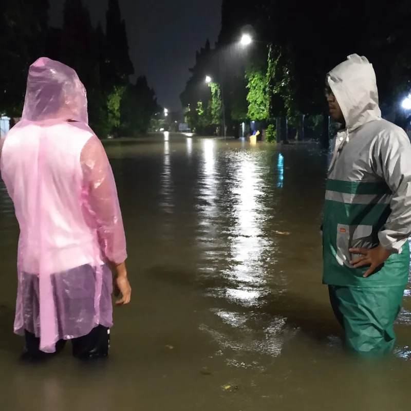 People standing in a flooded street with ponchos on