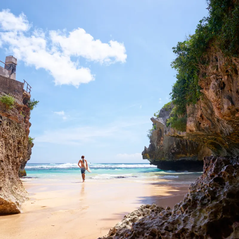 Surfer Walks Towards Ocean in Uluwatu Bali Beach.jpg